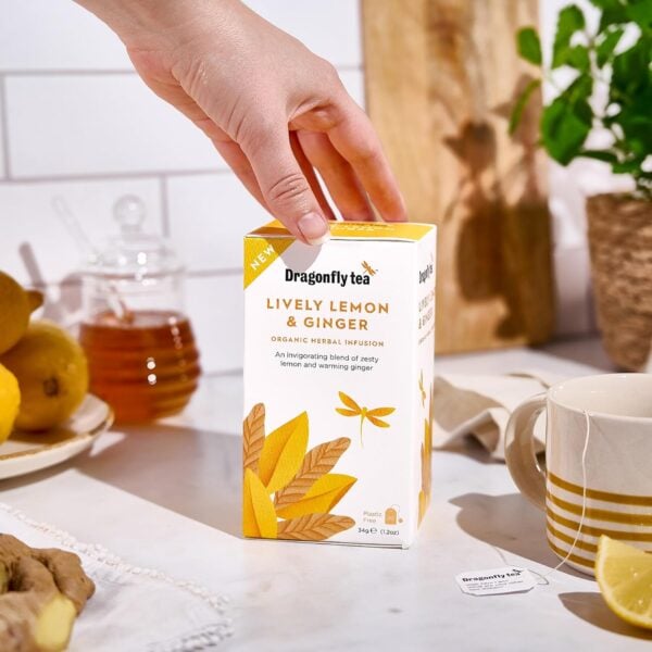 Dragonfly Organic Lively Lemon And Ginger, 20 Tea Bags 34G, Box On Tabel With Brewing Mug Of Tea, Available At Teas.co.uk